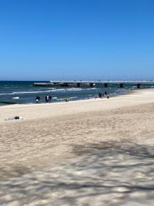 una playa de arena con un muelle en el océano en TOMALE-AMT Apartamenty Kasprowicza Kołobrzeg - basen, jacuzzi, sauna, siłownia w cenie apartamentu, en Kołobrzeg