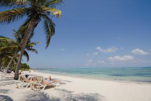 a beach with chairs and palm trees and the ocean at VR CLUB Tulum Riviera in Tulum