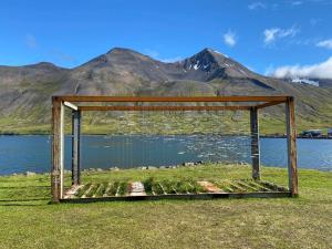una estructura de madera sentada en la hierba cerca de un cuerpo de agua en The Herring House en Siglufjörður