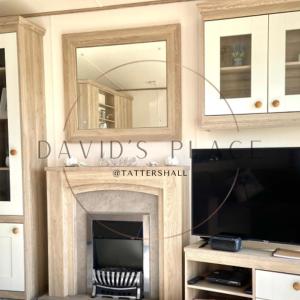 a living room with a fireplace and a mirror at David's place at Tattershall lakes in Tattershall