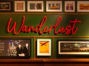 a sign that reads wanderlust on a wall with pictures at ibis Styles London Gatwick Airport in Crawley