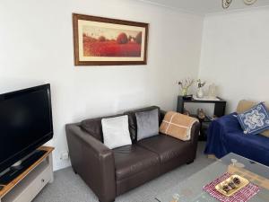 a living room with a leather couch and a flat screen tv at Family & Contractors Complementary Wine Coffee Tea in Earith
