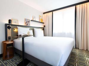 a bedroom with a large white bed and a window at Mercure Paris Bercy Bibliothèque in Paris