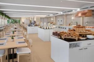 a restaurant with white tables and chairs and a bakery at Meliá Lloret de Mar in Lloret de Mar