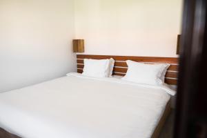 Schlafzimmer mit einem Bett mit weißer Bettwäsche und Kissen in der Unterkunft PenichePraia - Bungalows, Campers & SPA in Peniche
