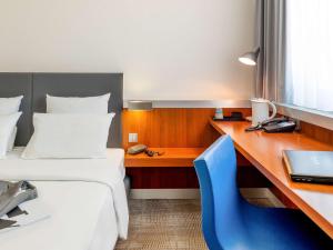 a hotel room with a desk and a bed and a blue chair at Novotel Erlangen in Erlangen