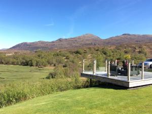 una casa con terraza con montañas al fondo en Maol View Apartment, en Kyleakin