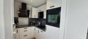 a kitchen with white cabinets and black appliances at Bungalow 2243 in Tossens in Butjadingen