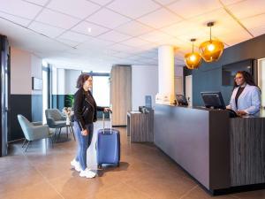 una mujer de pie en una oficina con una maleta en ibis Styles Hotel Brussels Centre Stéphanie, en Bruselas