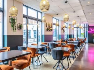 a row of tables and chairs in a restaurant with windows at ibis Styles Hotel Brussels Centre Stéphanie in Brussels