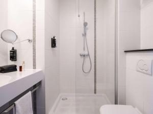 a white bathroom with a shower and a toilet at ibis Styles Hotel Brussels Centre Stéphanie in Brussels
