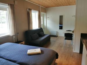 een slaapkamer met een bed, een bank en een stoel bij Telemark Motel and Apartment in Hauggrend