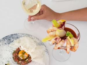 a person holding a glass of wine next to a plate of shrimp at Sofitel Noosa Pacific Resort in Noosa Heads