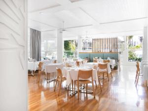 une salle à manger avec des tables et des chaises blanches dans l'établissement Sofitel Noosa Pacific Resort, à Noosa Heads