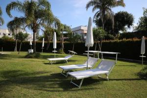 three lounge chairs and umbrellas on the grass at MARGIE'S HOUSE in Procida