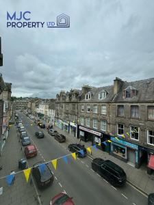 a city street with cars parked on the street at Cross Wynd Apartment in Hawick