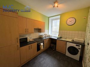 a kitchen with wooden cabinets and a clock on the wall at Cross Wynd Apartment in Hawick