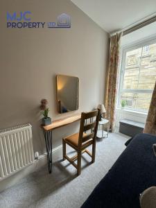 a bedroom with a desk with a mirror and a chair at Cross Wynd Apartment in Hawick