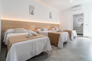 a group of four beds in a room at Casa rural Villa Gordito in La Lantejuela +42 photos