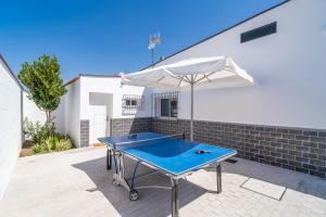 a ping pong table with an umbrella on a patio at Casa rural Villa Gordito in La Lantejuela