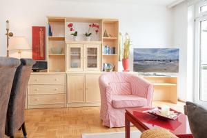 een woonkamer met een roze stoel en een tafel bij Seestraße 55 Ostseeperle in Scharbeutz