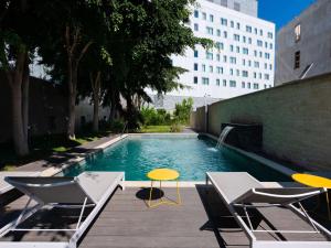 a swimming pool with two chairs and a table at Novotel Convention And Spa in Antananarivo