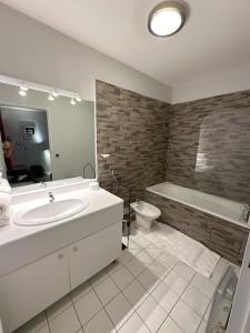 uma casa de banho com um lavatório, uma banheira e um WC. em Appartement Grand Veneur CityCosy em Paris