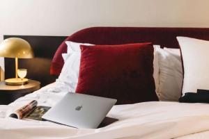 laptopa siedzącego na łóżku w obiekcie The Capitol Hotel Sydney w mieście Sydney