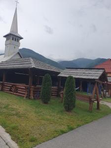 een houten gebouw met een toren en een kerk bij Pensiunea ACASA LA VLADUȚ in Borşa