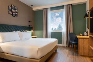 a hotel room with a bed and a desk and a window at Hilton Garden Inn Milan Malpensa in Somma Lombardo