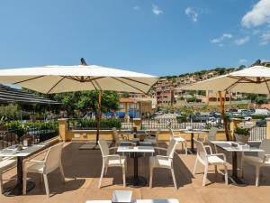 un patio avec tables, chaises et parasols dans l'établissement Casa Pisano, à Villasimius