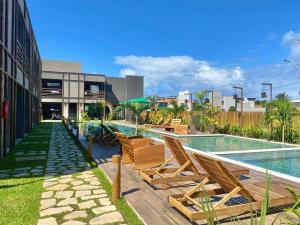 une piscine avec des chaises longues à côté d'un bâtiment dans l'établissement Apto 001 B GAMBOA, à Porto de Pedras