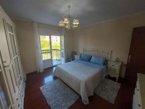 a bedroom with a bed and a window and a chandelier at INcostadamorte Vivienda Martinez in Cee