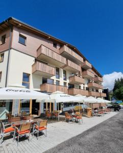 a large building with tables and chairs and umbrellas at Alpenstyle Resort Fieberbrunn by AlpenTravel in Fieberbrunn
