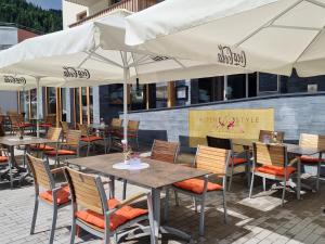 an outdoor patio with tables and chairs with umbrellas at Alpenstyle Resort Fieberbrunn by AlpenTravel in Fieberbrunn