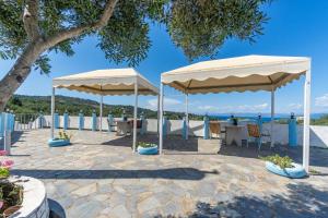 a patio with two white umbrellas and tables at Paco's Superior Double Villa 15 in Oziás