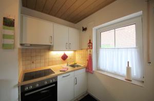 eine Küche mit weißen Schränken, einem Waschbecken und einem Fenster in der Unterkunft Jautz RE13 in Sögel
