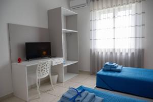 a white room with a tv and a desk with a chair at Mare Fuori casa vacanze in Castellammare di Stabia
