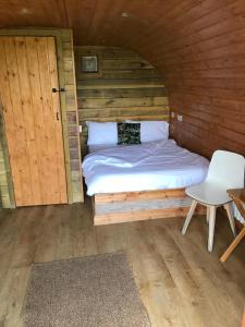 a bed in a wooden cabin with a table and a chair at Crabmill Glamping with hot tub in Bewdley