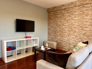 a living room with a couch and a tv on a brick wall at Casa Mirador del Pas - Monabri in Boó de Piélagos