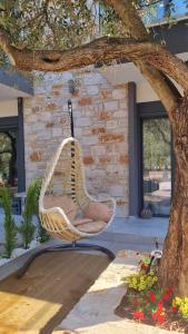 une chaise en osier assise sur une terrasse couverte sous un arbre dans l'établissement Danielli Luxury Villas, à Skala Rachoniou