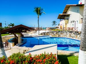 a swimming pool with a palm tree and a building at Sunset Beach Villas in Taíba
