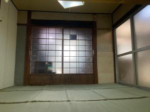 um quarto vazio com uma porta e janelas em しまなみゲストハウス南風荘 em Imabari