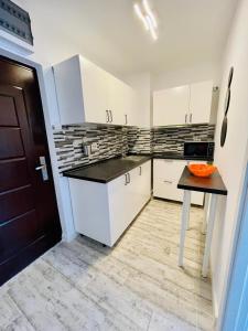 a kitchen with white cabinets and an orange bowl on a table at Apartament Olimp in Olimp +4 photos