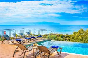 a balcony with chairs and a swimming pool and the ocean at Villa Louloudia in Ratzaklíon