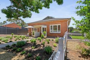 a brick house with a fence in front of a yard at 1930's Character Cottage - Beautifully Restored in McLaren Vale