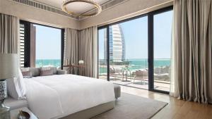 - une chambre avec un grand lit blanc et de grandes fenêtres dans l'établissement Jumeirah Al Naseem Dubai, à Dubaï