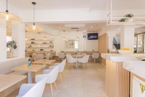 a restaurant with wooden tables and white chairs at Hotel Gabarda in Palmanova