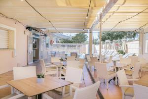 un restaurante vacío con mesas y sillas blancas en Hotel Gabarda, en Palmanova