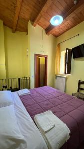 un grande letto in una stanza con una coperta viola di da sciuri case vacanza barisciano a Barisciano